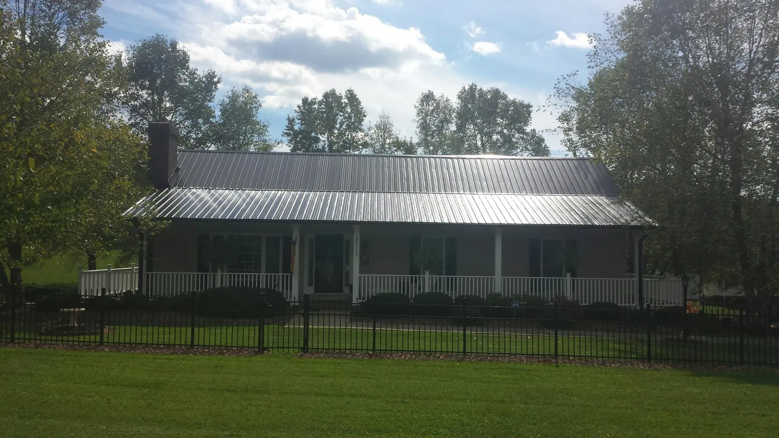 Gray metal roof on a brick ranch with a full width front porch in Dixon